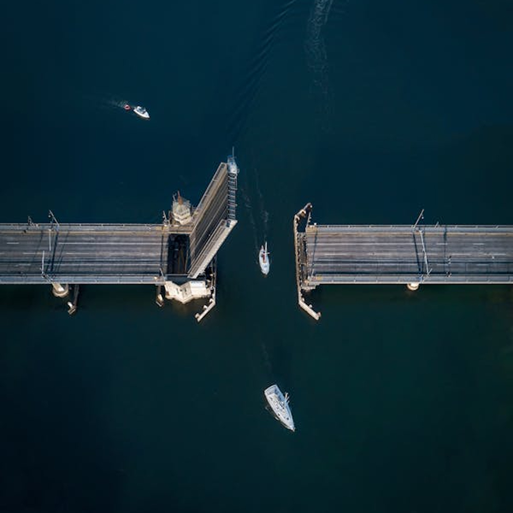 Aerial view of an open swing bridge with boats passing through